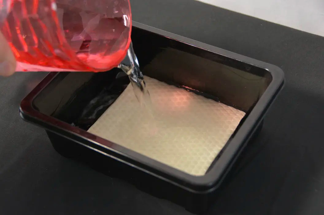 Seed starter tray bottom watering system with absorbent grow mat being filled with nutrient solution