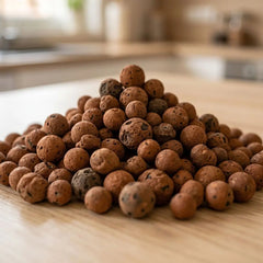 Close-up of brown clay pebbles, a natural growing medium for home hydroponic systems, piled on a wood countertop